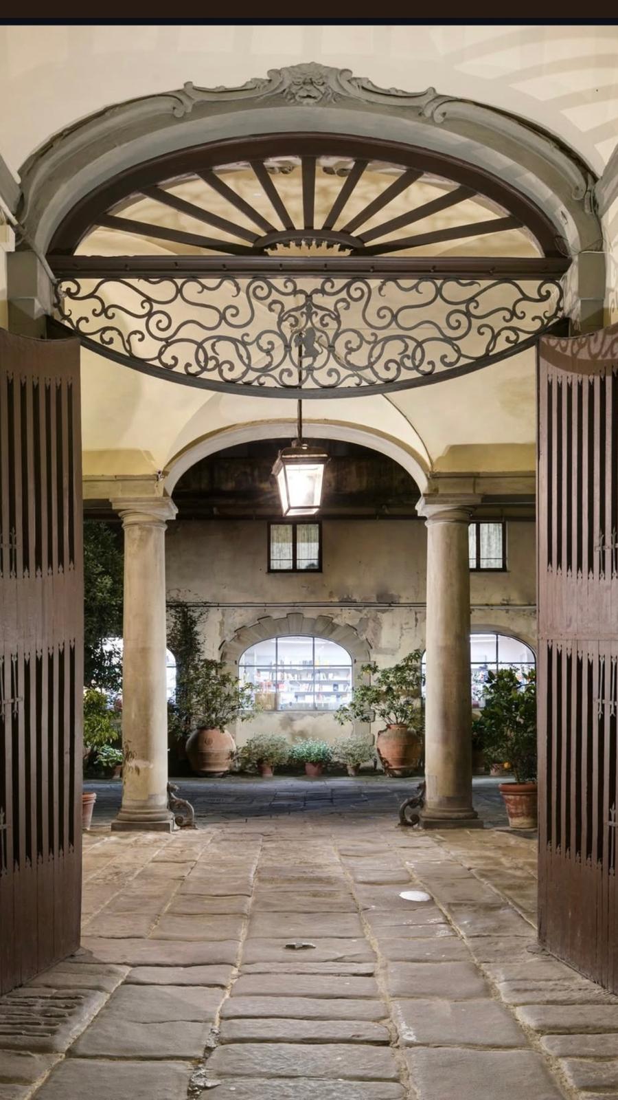Corte interna di Palazzo Niccolini con arco in pietra, colonne della loggia e orci in terracotta