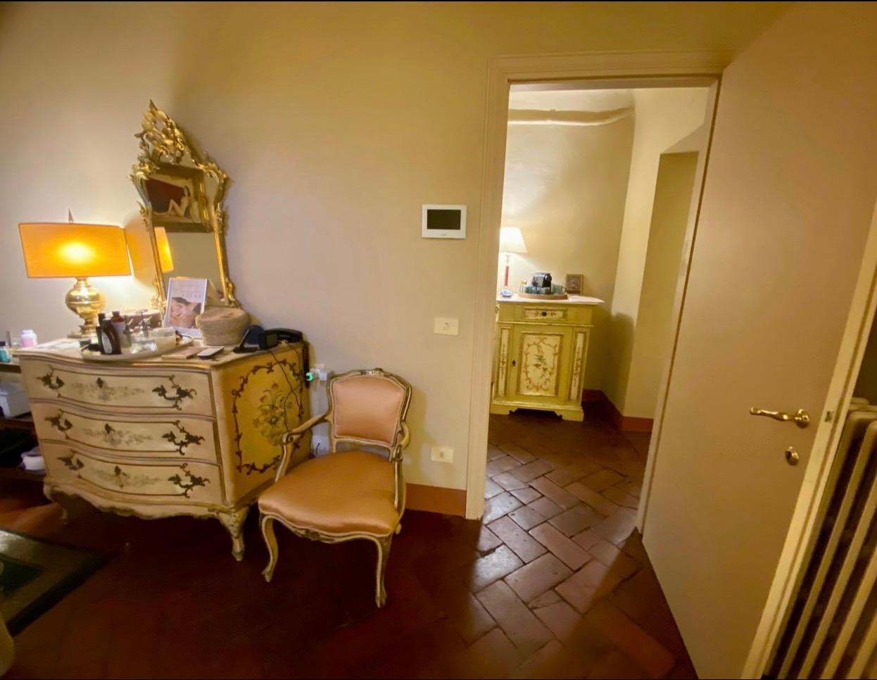 Angolo con comò d'epoca, specchiera dorata e porta aperta verso la sala successiva