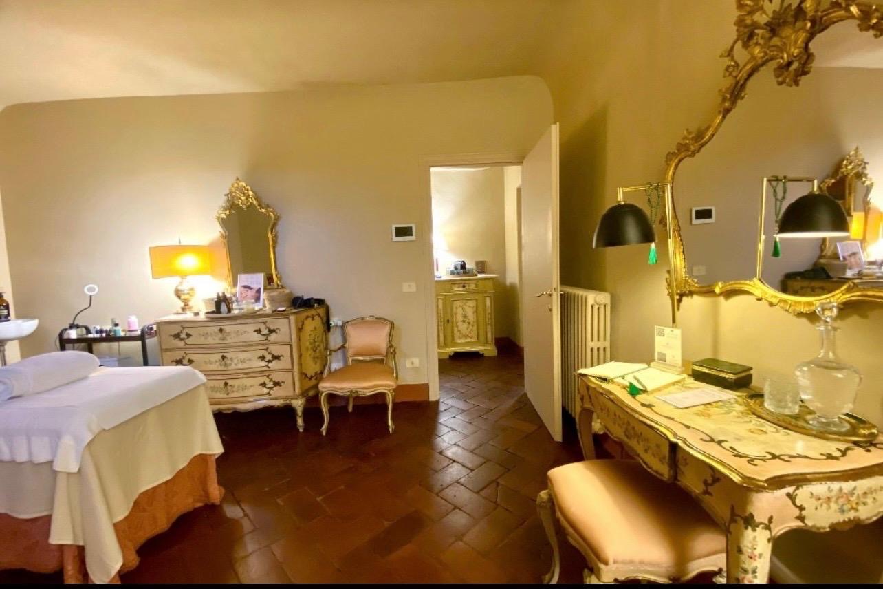 Sala di accoglienza con specchiera dorata, comò dipinto e lettino preparato