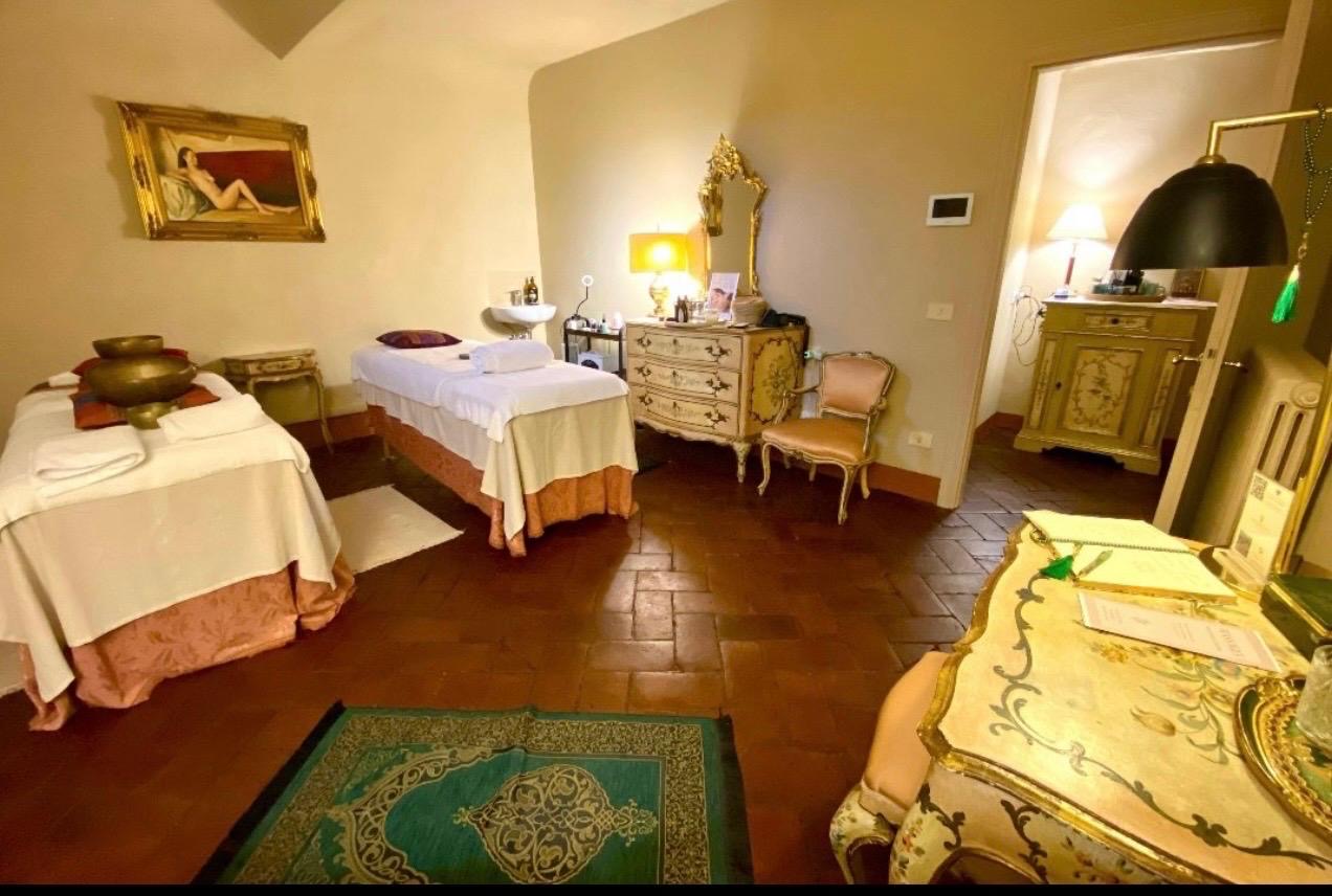 Sala dei trattamenti con due lettini, campane tibetane e poltrona in velluto rosa