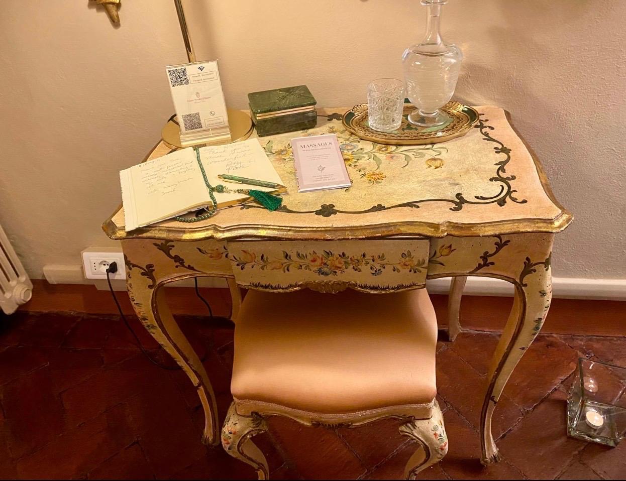 Scrivania settecentesca dipinta a fiori con libricino dei massaggi e caraffa d'acqua